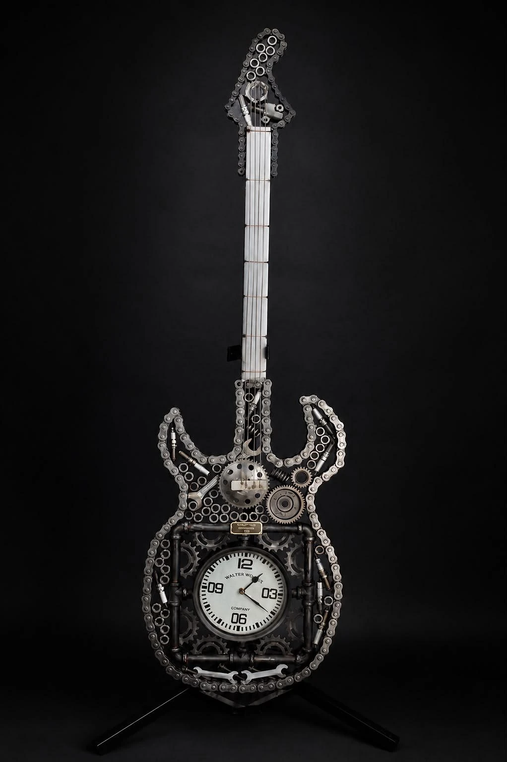 Timeless Steel — gitaarsculptuur van kettingen, tandwielen en pijp, met een werkend uurwerk in het corpus